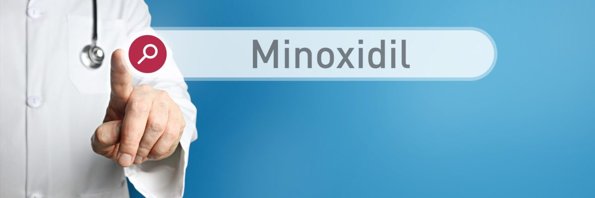 Minoxidil. Doctor in smock points with his finger to a search bo